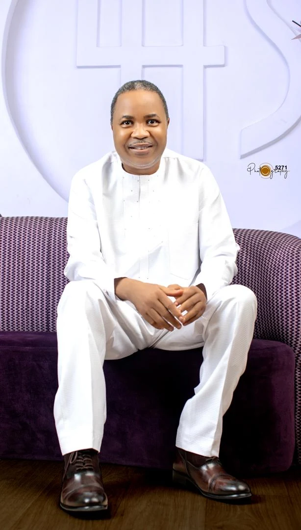 Reverend Dr. Adamson Aromaegbe in white attire, seated for a portrait.